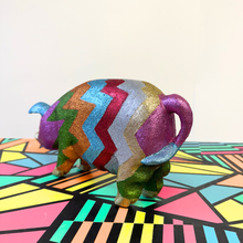Load image into Gallery viewer, Colorful upcycled glittery wooden pig on a geometric-patterned surface