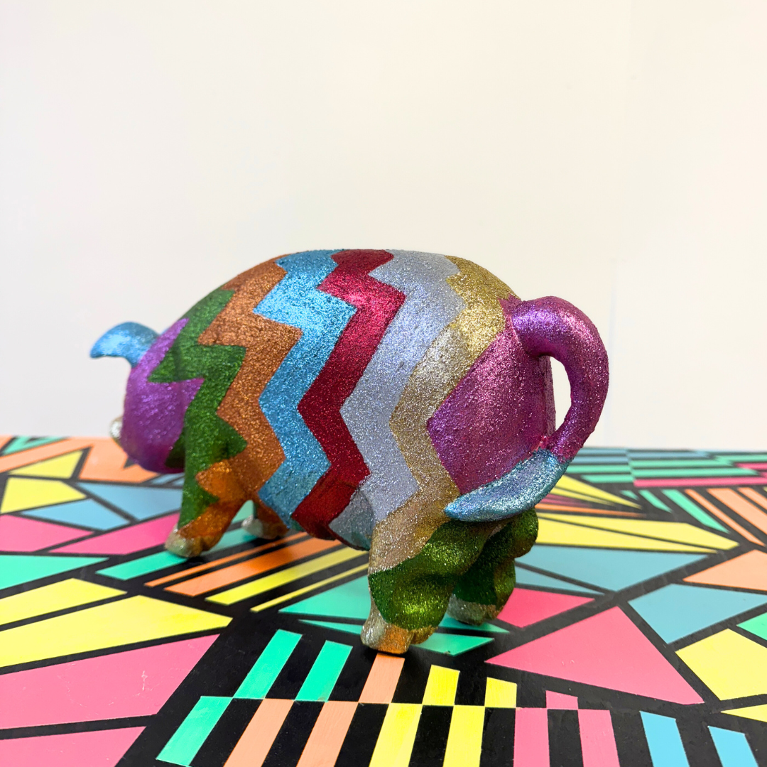 Colorful upcycled glittery wooden pig on a geometric-patterned surface