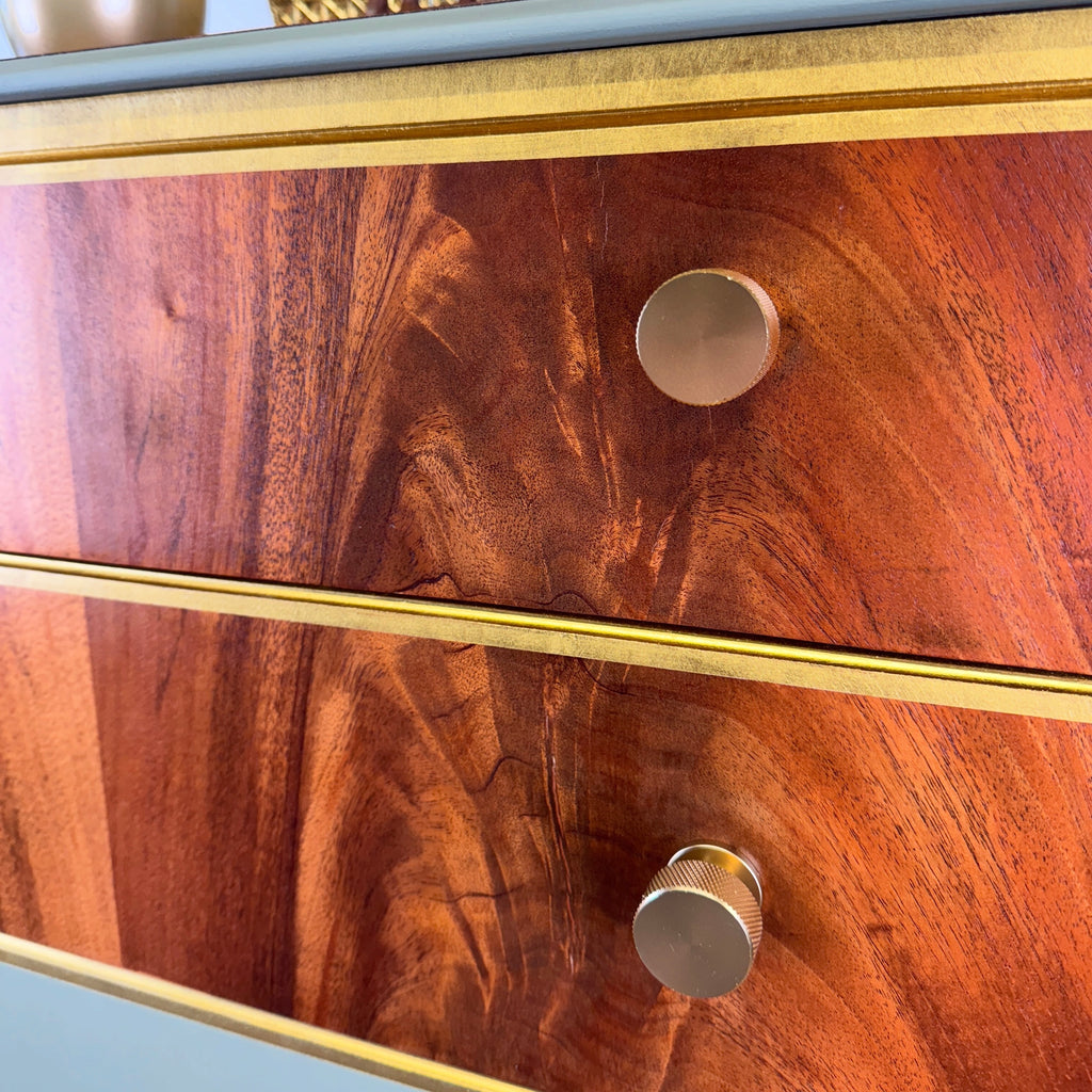 Wooden drawer with gold trim and knobs on a light green background