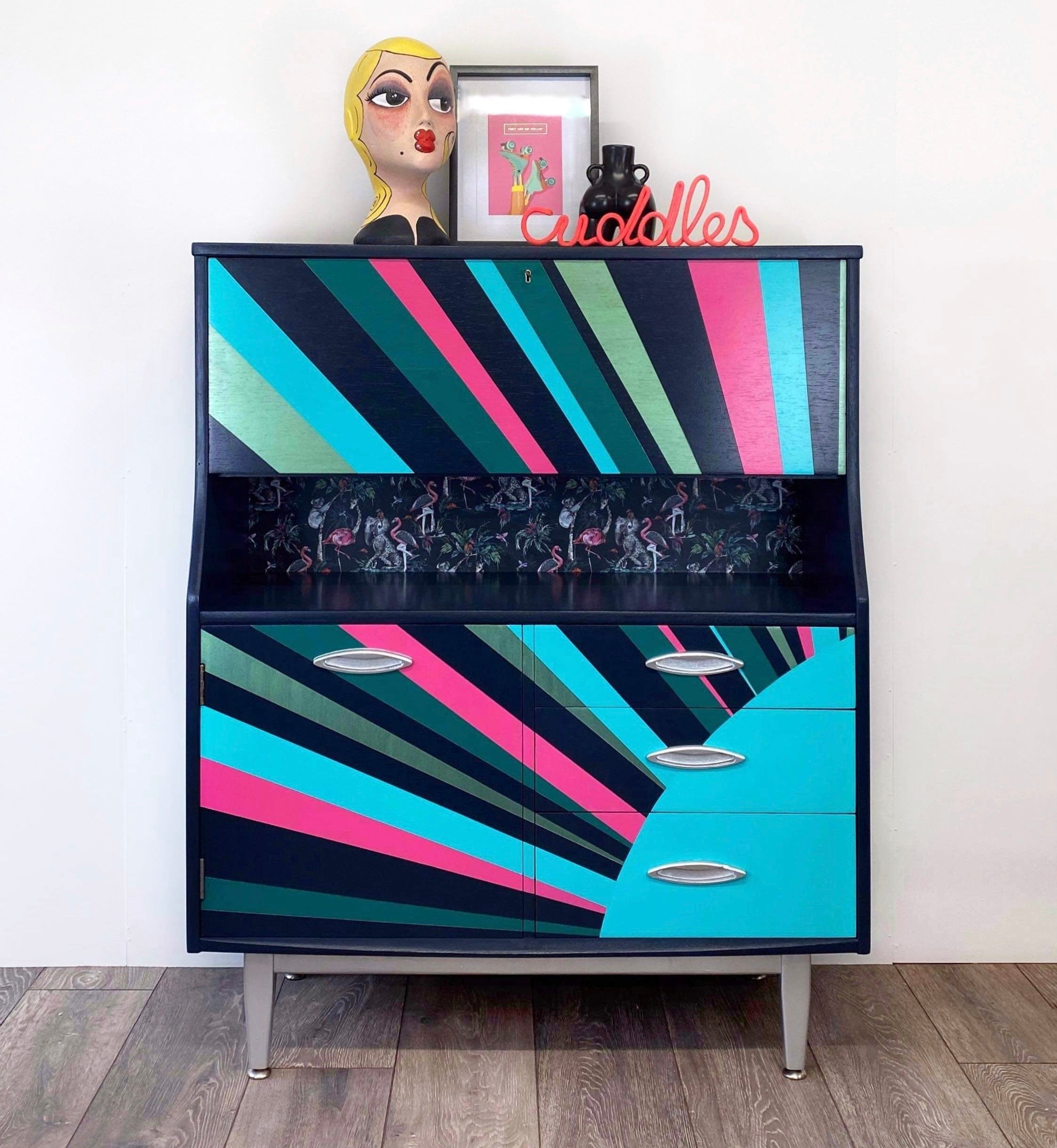 mid century bureau turned into a drinks cabinet and painted in blue pink and silver sunburst design