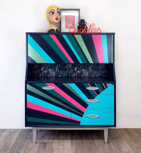 Load image into Gallery viewer, mid century bureau turned into a drinks cabinet and painted in blue pink and silver sunburst design
