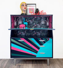 Load image into Gallery viewer, mid century bureau turned into a drinks cabinet and painted in blue pink and silver sunburst design
