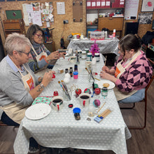 Load image into Gallery viewer, Three people sitting around a table painting ceramic christmas baubles
