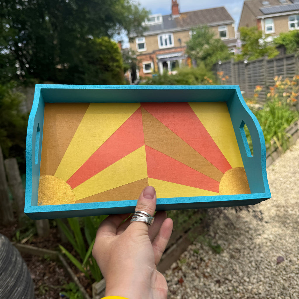 Colorful geometric-patterned tray held by a person outdoors with buildings and trees in the background