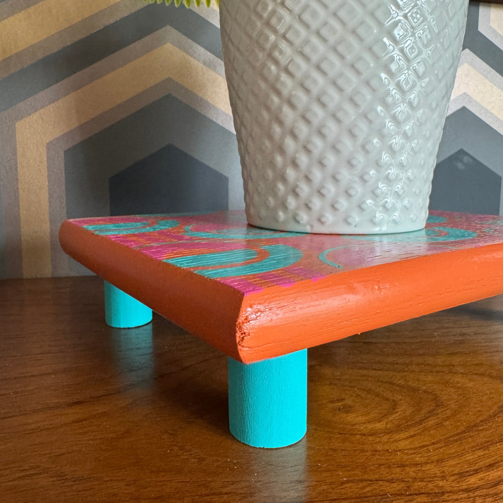 Handpainted reclaimed wooden plant stand displaying a houseplant on a colourful handmade wooden riser made from reclaimed wood.