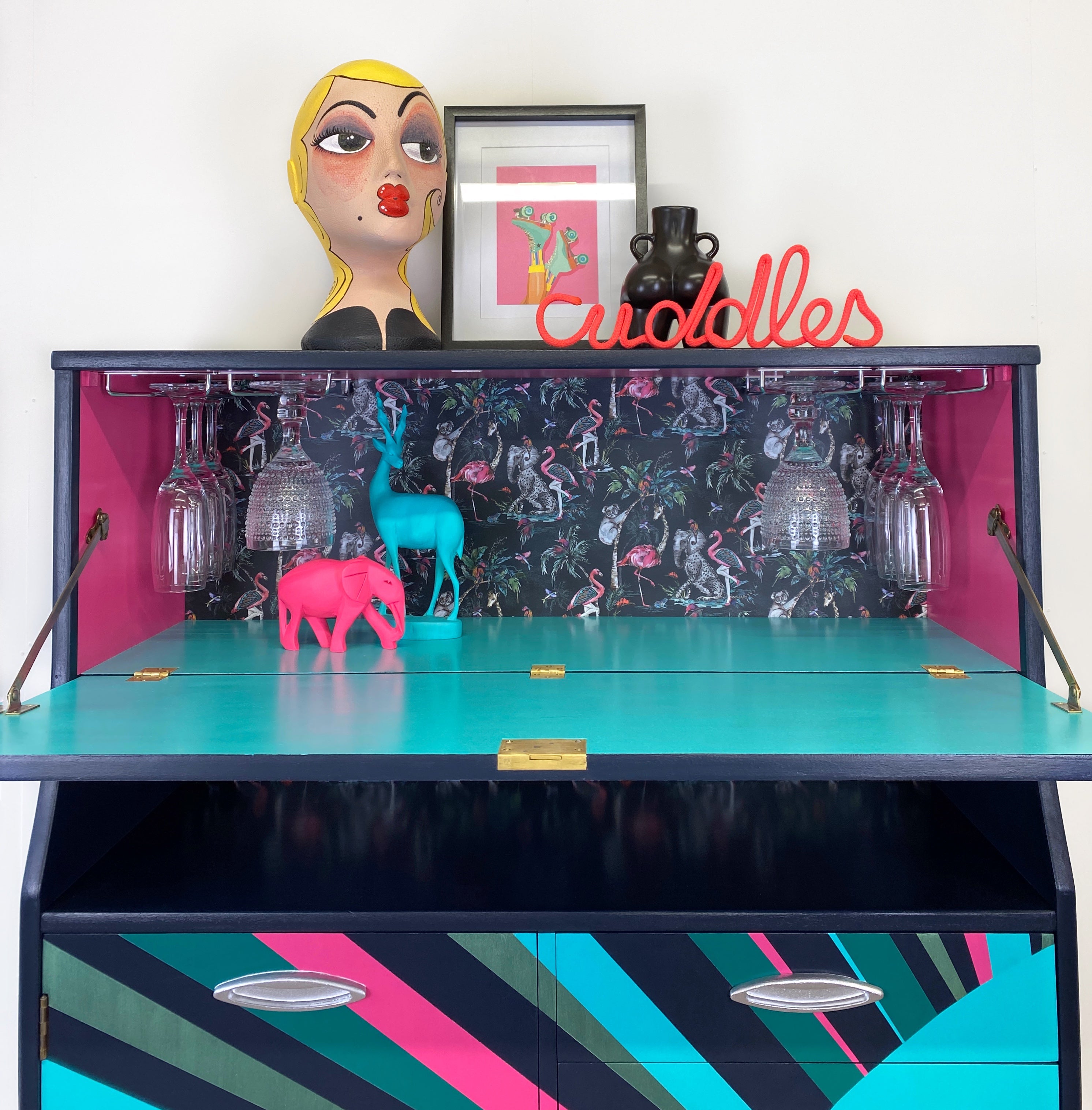 mid century bureau turned into a drinks cabinet and painted in blue pink and silver sunburst design
