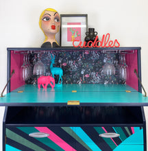 Load image into Gallery viewer, mid century bureau turned into a drinks cabinet and painted in blue pink and silver sunburst design
