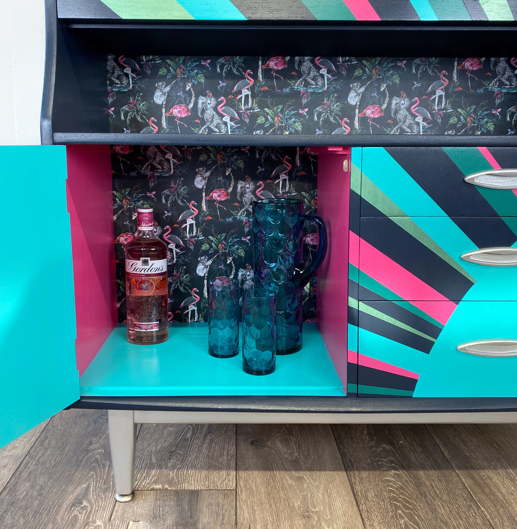 mid century bureau turned into a drinks cabinet and painted in blue pink and silver sunburst design