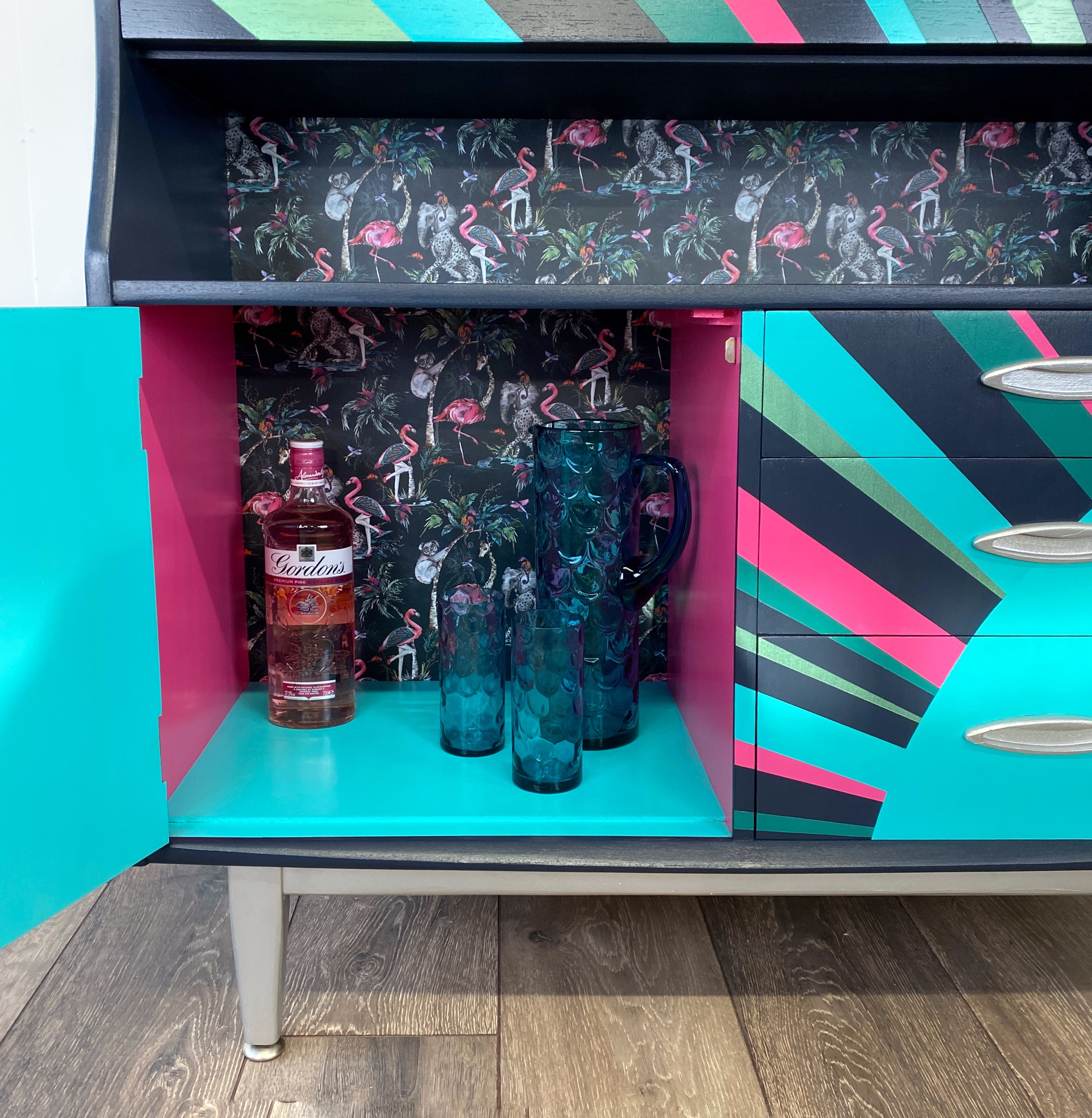 mid century bureau turned into a drinks cabinet and painted in blue pink and silver sunburst design