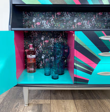 Load image into Gallery viewer, mid century bureau turned into a drinks cabinet and painted in blue pink and silver sunburst design
