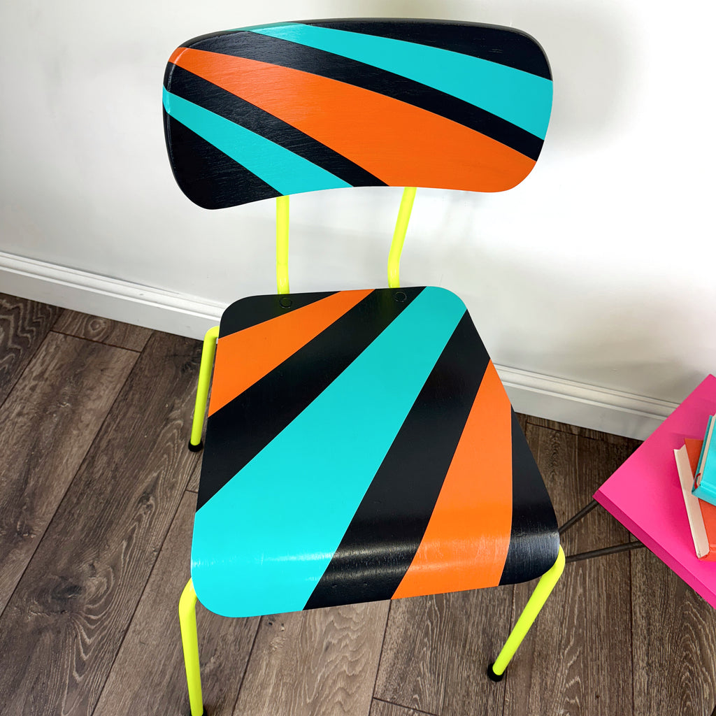 chair with neon yellow legs painted with an orange, blue and black geometric design