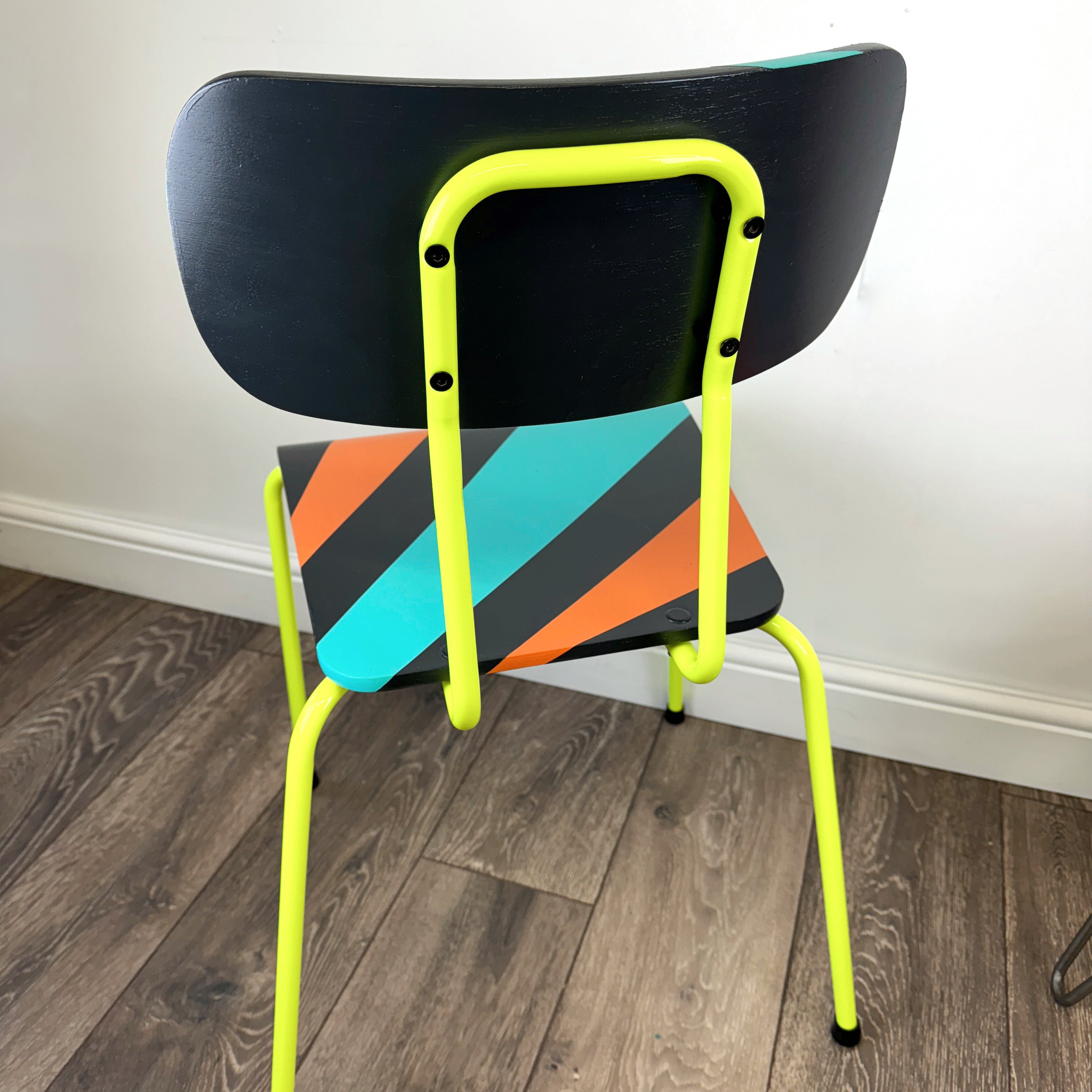 chair with neon yellow legs painted with an orange, blue and black geometric design