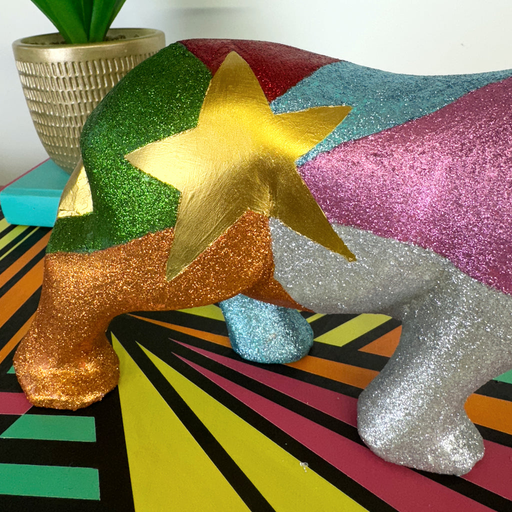 Large wooden rhinoceros handpainted in bright colours, glitter and a gold star design