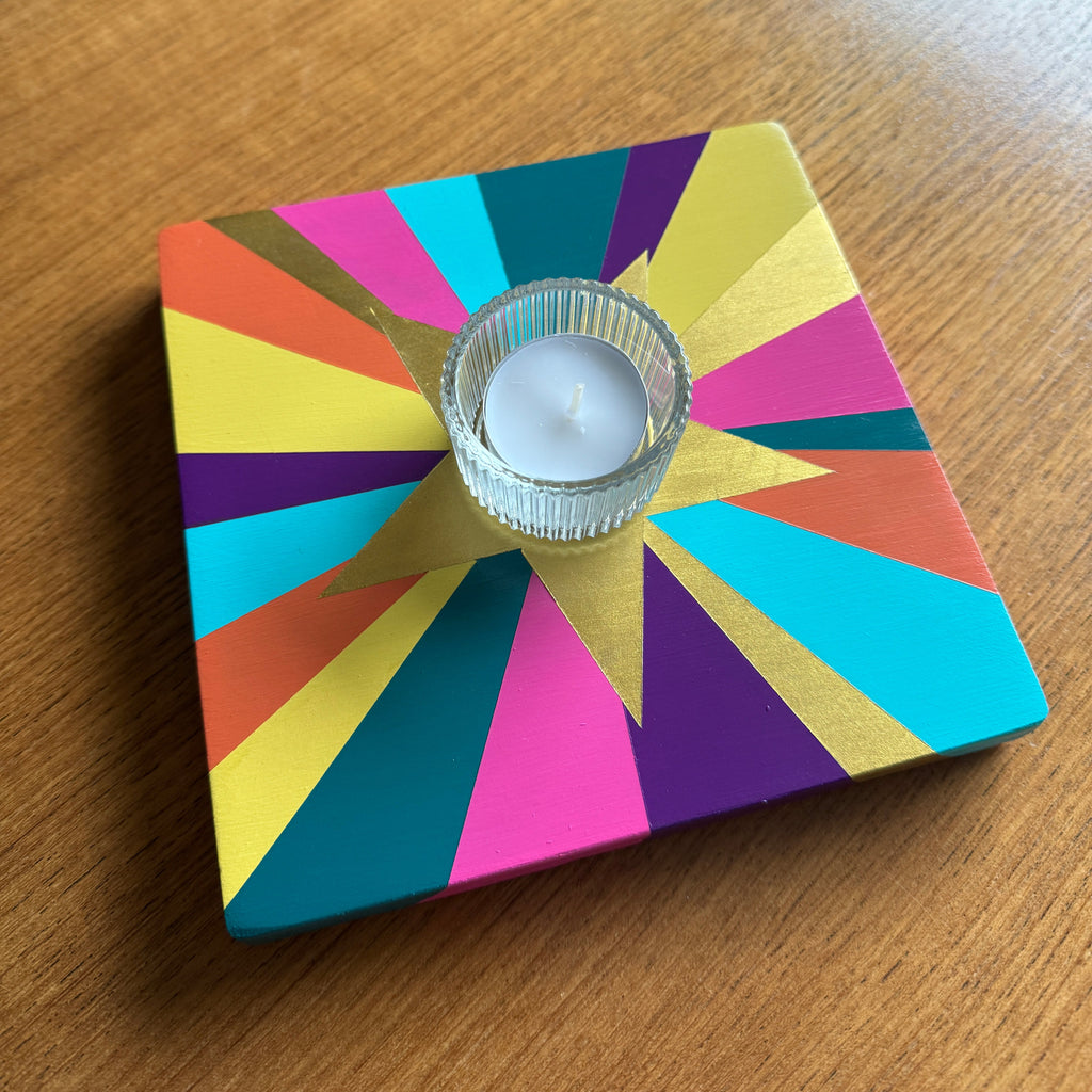 Painted reclaimed wooden candle holder with bright rainbow colours and a gold star