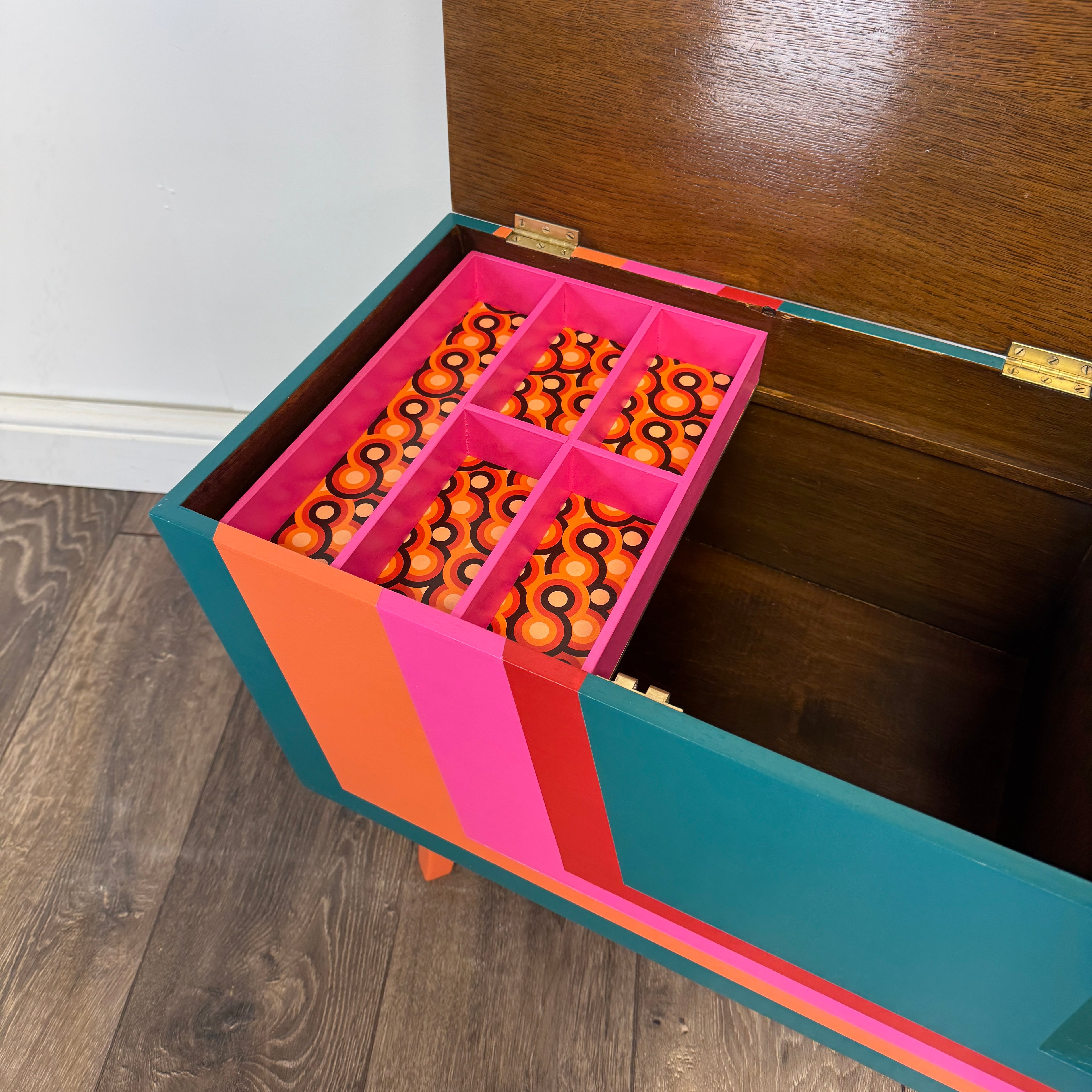 Colorful striped mid century sewing box with a pink elephant figurine on a plain background