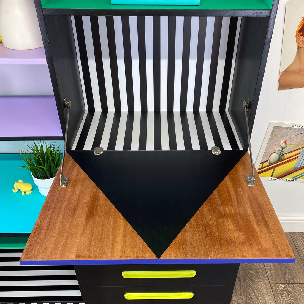 Bright yellow, blue, green, pink and lilac painted mid century storage unit with black and white striped detail