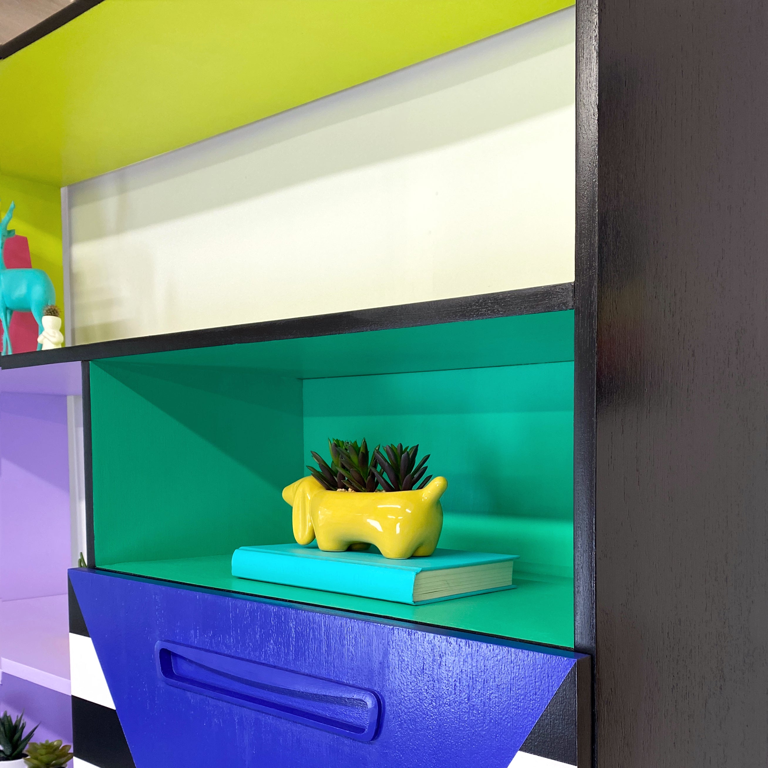Bright yellow, blue, green, pink and lilac painted mid century storage unit with black and white striped detail